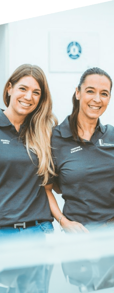 2 Frauen gekleidet mit grauem Polo und der Aufschrift Autohaus Linck sowie blauer Jeans