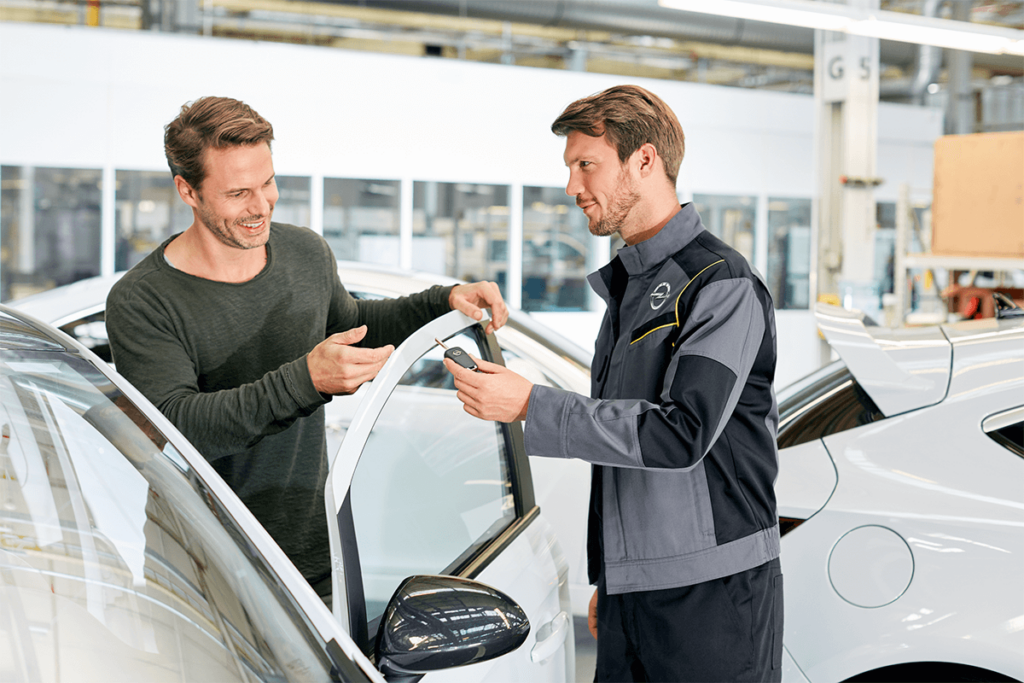 Ein Mitarbeiter der Marke Opel übergibt einen Kunden den Autoschlüssel für sein Fahrzeug